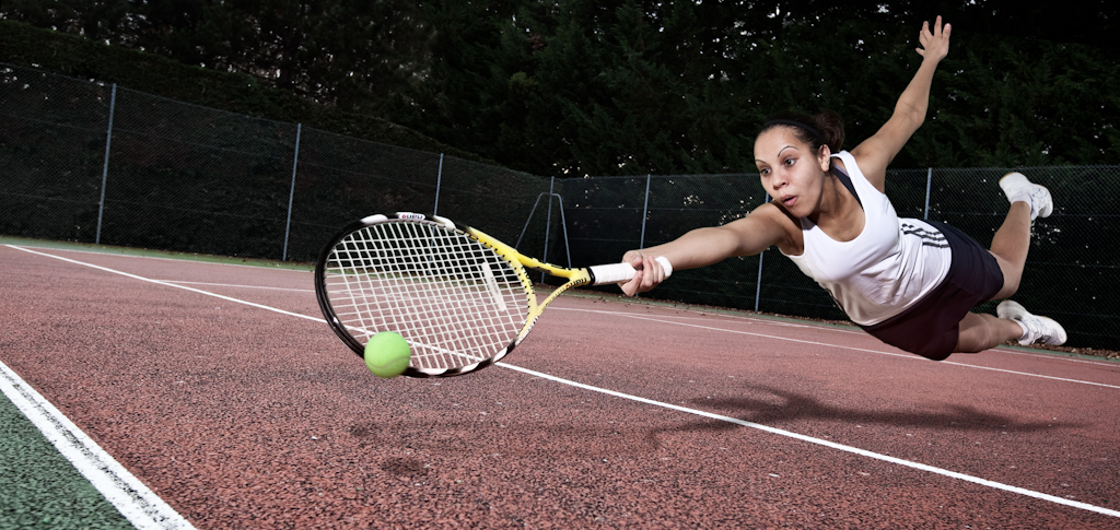 Tennis player dives for a low ball. Commercial advertising style image.